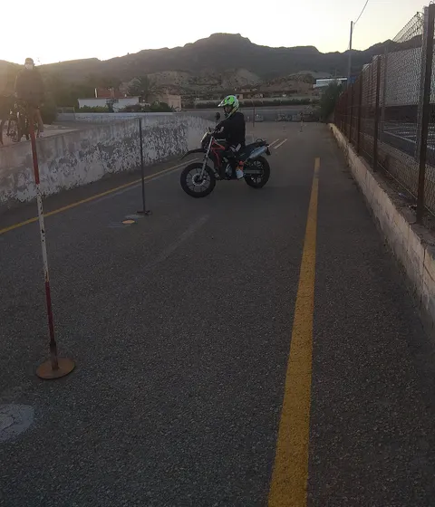 Alumno con casco haciendo prácticas de moto en la pista